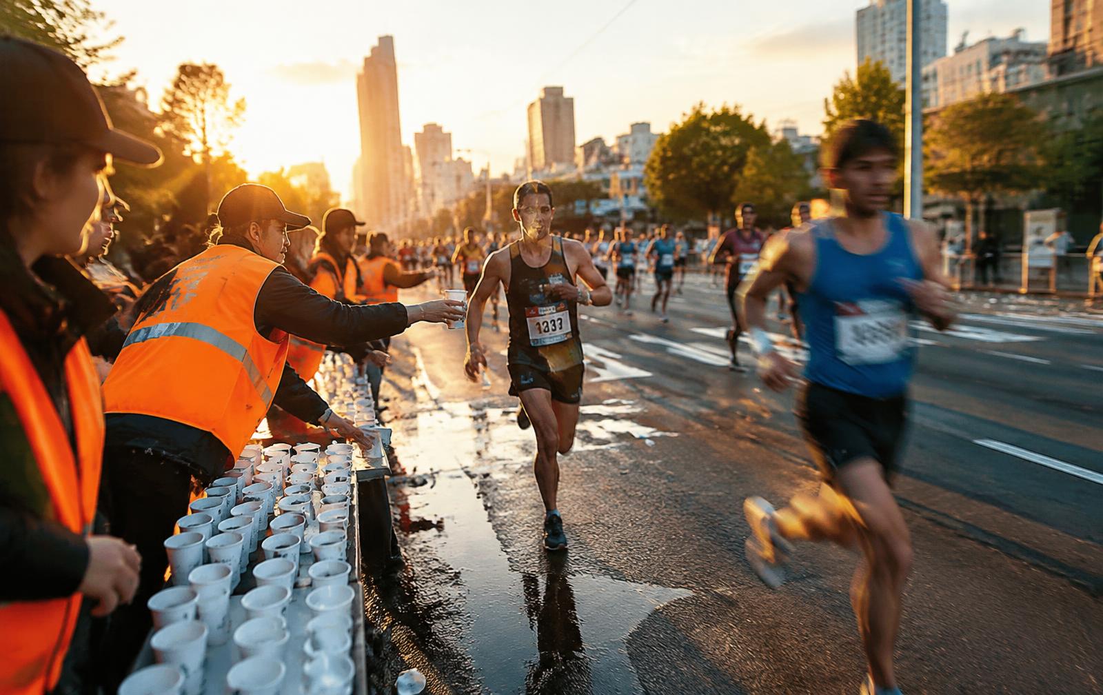 Voluntários entregando água a corredores